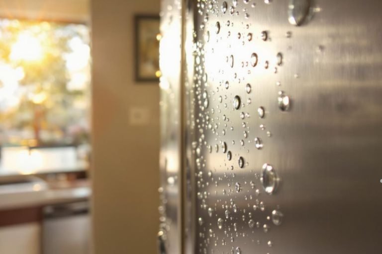 A refrigerator door glistening with water droplets, reflecting light and showcasing a cool, refreshing appearance.